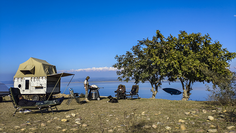 Young boys enjoying camping in wilderness with campervan around pong dam in himachal for offbeat camp holiday which is safe from corona safe with social distancing india. 