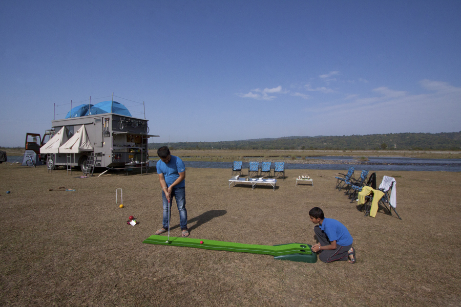 a family enjoying golf game with caravan campervan on the river banks. 