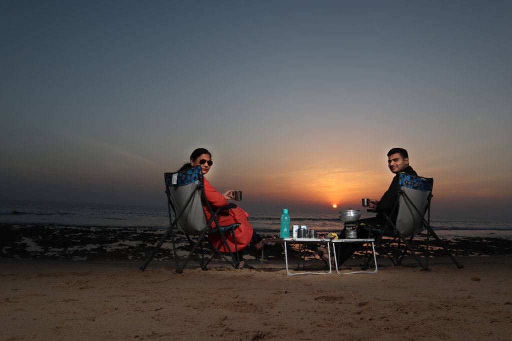 a couple enjoying romantic holidays onboard campervan caravan offbeat location in wilderness on a secluded beach at pingleshwar in kutch gujarat 