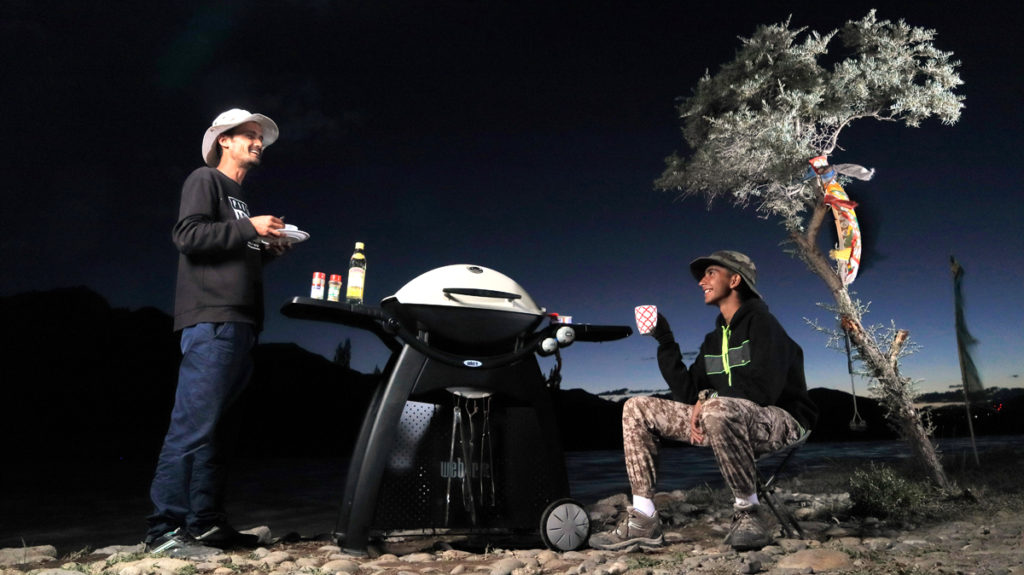 weber  Barbecue Grill is deployed for friends to enjoy a campervan caravan vacation in wilderness on the banks of river. 