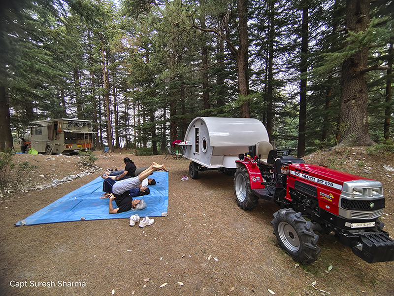 group of women doing yoga in jungle camp with caravan campervan dharamshala in himachal for offbeat outdoor nomadic camp holiday corona safe. 